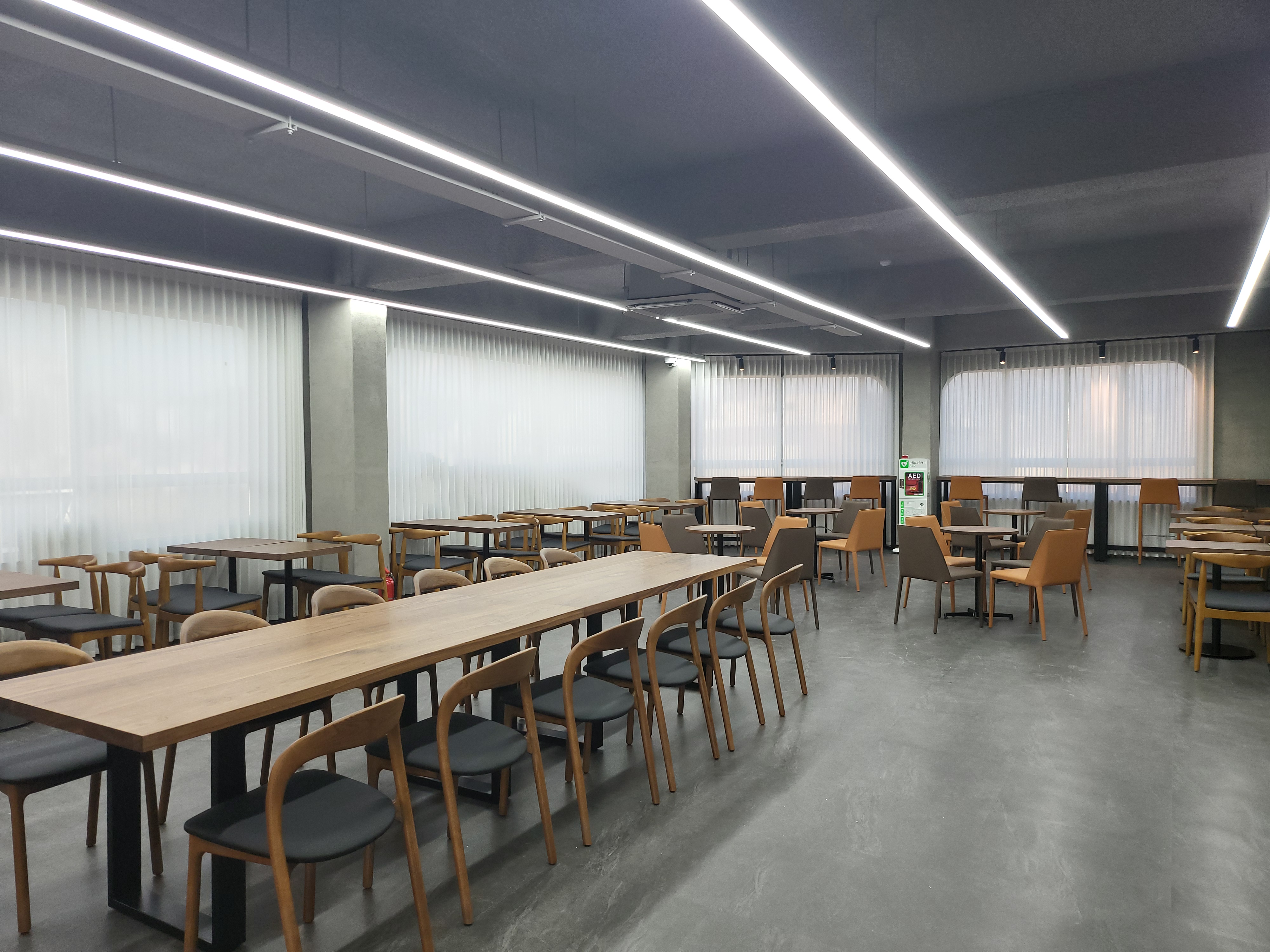 하얀 커튼 사이로 빛이 스며드는 카페 좌석 공간